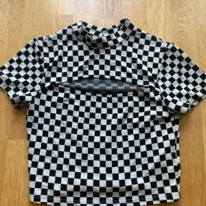 Svartvit rutig topp från new yorker - En svartvit rutig topp köpt på New Yorker. Med en unik cut-out detalj över bröstet som gör den perfekt för fester! Köpt för några år sedan. Pris kan diskuteras!