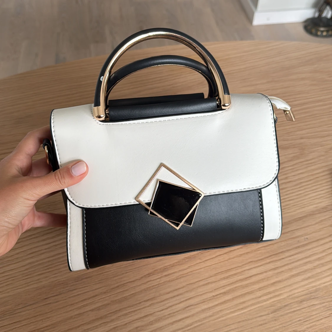 Svartvit handväska med gulddetaljer