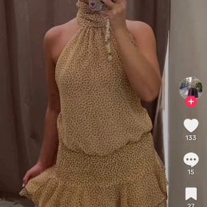 Gul blommig halterneckklänning Zara - Supersöt gul kort klänning från Zara med småblommigt mönster. Halterneck med hög krage, öppen rygg och volangig kjol. Lätt och flowy känsla, perfekt för varma dagar. Sitter snyggt och ger en chill men ändå trendig vibe. Storlek M, aldrig använd-lappen kvar!🥰