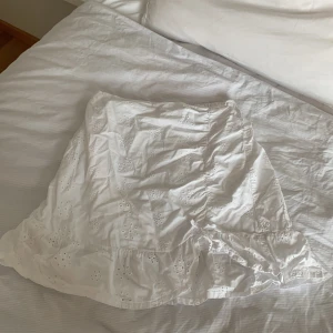 vit broderad kortkjol - H&M - superfin vit kortkjol från H&M med broderade blommor och volangkant! kjolen har en söt knytning framtill och är gjord av mjuk bomull, perfekt till varma dagar! använd mycket men har inga jättestora defekter!