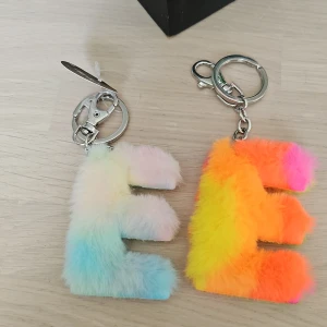 Färgglada pälsiga E-nyckelringar Tinka - Två fluffiga nyckelringar från Tinka i form av bokstaven E. Ena är pastellfärgad i ljusblått, rosa och vitt, den andra är neonfärgad i orange, gul, rosa och grön. Båda har metallring och karbinhake. Perfekt accessoar till väskan eller nycklarna.