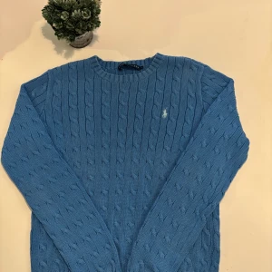 Blå kabelstickad tröja från Ralph Lauren - Säljer en blå kabelstickad tröja från Ralph Lauren. Tröjan har rund halsringning och långa ärmar. Skicket är mycket bra, strl är L men passar XS-S utmärkt. Hör av er vid frågor!
