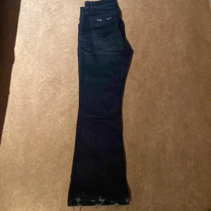 Mörkblå bootcut jeans - Snygga mörkblå bootcut jeans med en klassisk femficksdesign. Jeansen har en lätt utsvängd passform som ger en retro känsla. Perfekta för en avslappnad stil.