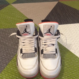 Nike Air Jordans i vitt och svart - Snygga Nike Air Jordans i vitt med svarta och röda detaljer. Skorna har den klassiska Jumpman-loggan på tungan och hälen. Perfekta för dig som vill ha en stilren och sportig look.