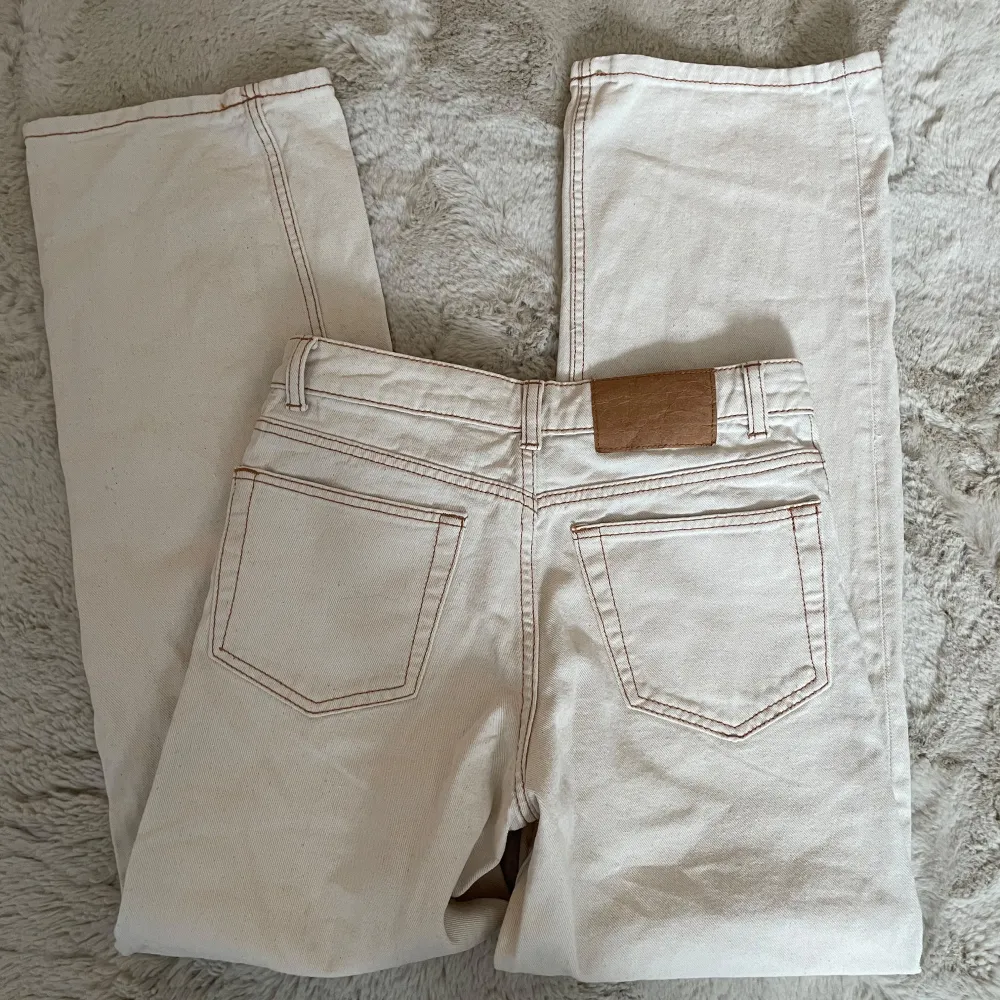 Snygga beige jeansbyxor med en klassisk femficksdesign. Byxorna har en rak passform och är perfekta för en avslappnad stil. De har en knapp och dragkedja framtill samt bälteshällor.. Farkut & Housut.