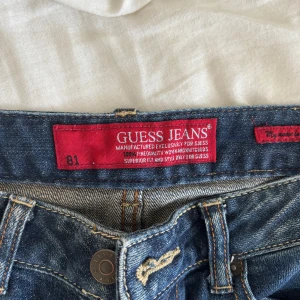 Jeansshorts från Guess - Snygga jeansshorts från Guess i klassisk blå denim. De har en normal passform och är perfekta för sommardagar. Shortsen har en ikonisk Guess-logga på bakfickan och en bekväm midja.