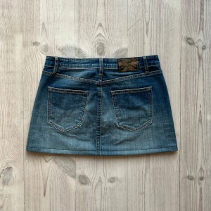 Blå lågmidjad jeanskjol  - Blå lågmidjad jeanskjol från Crocker som jag har sytt upp från en längre kjol. Fint skick. Storlek S men skulle säga att den även passar M. Tvärs över midjan är det 39 cm och den är 33 cm lång. Använd gärna köp nu!