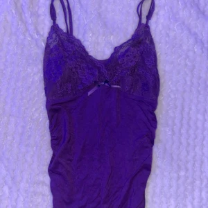 Lila spetslinne med rosett - Snyggt lila linne med spetsdetaljer och en liten rosett framtill. Storlek XS💜