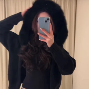 alessa svart jacka - Mysig svart teddyjacka med stor huva. Perfekt för kyliga dagar. Jackan har långa ärmar och en loose passform som ger en avslappnad look.