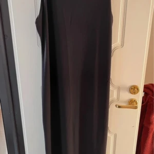 Svart långklänning från Gina Tricot - Elegant svart långklänning från Gina Tricot. Klänningen är ärmlös och har en stilren design som passar perfekt för olika tillfällen. Tillverkad i ett mjukt och följsamt material som ger en bekväm passform.