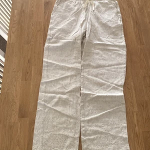 Beigea linnebyxor med snörning - Snygga och bekväma vita linnebyxor med snörning i midjan. Perfekta för en avslappnad stil med en luftig passform. Byxorna har en rak design och är tillverkade i ett lätt och andningsbart material. Storlek Large i ubgdomsstolek