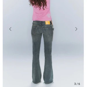 Mörkblå bootcut jeans med kedjedetalj - Snygga mörkblå bootcut jeans med låg midja. Perfekta för en avslappnad stil med en touch av edge. Klassisk femficksdesign och knappgylf.