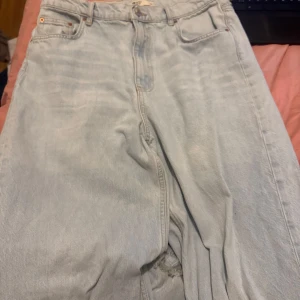 Ljusa jeans  - Säljer ett par ljusa jeans från HM de är high waist och är straight leg. De är köpta från Ginatricot ett år sen och har aldrig på mig för gillar inte baggy stilen längre. Storleken är 40 och perfekta för dig dom vill ha en lite mer baggy look. De har lite slitningar på änden men inget märkvärdigt se bild två!!