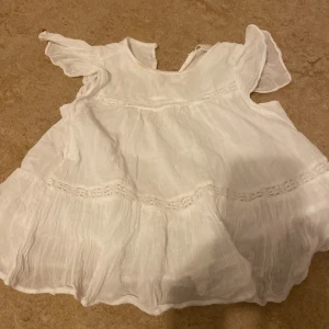 Vit blus  från Gina Tricot❤️ - Charmig vit klänning från Gina Tricot med korta ärmar och volangdetaljer. Perfekt för varma dagar med sitt luftiga och lätta material. Klänningen har en söt och lekfull design som passar bra för sommarens äventyr.