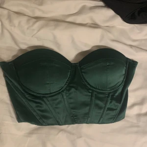 Grön satin korsett topp - En grön korsett topp med snörning på ryggen. Kuporna är redan vadderade så de håller formen fint när man har på sig den. Jag har använt den en kväll bara💚 passar både xs och S
