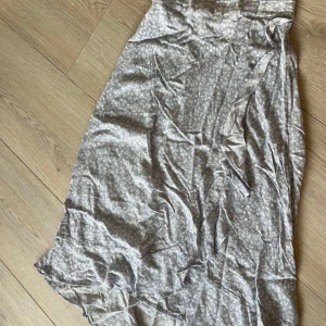 Blommig kjol från Lindex - Säljer en söt blommig kjol från Lindex i ljusblått med vita blommor. Kjolen har en bekväm resår i midjan och är perfekt för varma dagar. Den är tillverkad i ett mjukt och lätt material som ger en luftig känsla. Passar perfekt för sommarens alla äventyr! 🌸