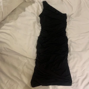 Svart oneshoulder klänning från Stradivarius - Snygg svart oneshoulder klänning från Stradivarius. Perfekt för en kväll ute med sin tighta passform och stilrena design. 