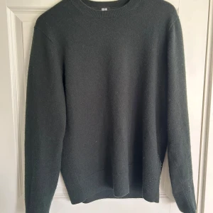 Kashmir tröja  - Säljer en stilren mörkgrön tröja från Uniqlo. Tröjan är långärmad och har en ribbad rund halsringning samt ribbade muddar vid ärmslut och nederkant. Perfekt för kyligare dagar. Tröjan är gjord av 100% kashmir!