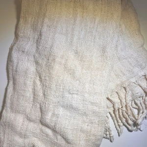 Beige halsduk med fransar - Säljer en stilren beige halsduk med fransar i ändarna. Den är perfekt för att hålla dig varm under kyliga dagar. Halsduken har en mjuk och bekväm känsla, vilket gör den till ett utmärkt tillägg till din garderob.