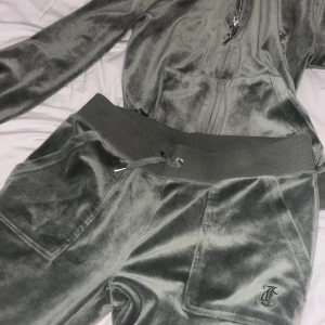 Juicy coutoure - Säljer en mjuk och bekväm grön juicy coutoure hoodie med matchande byxor. Hoodien har dragkedja och en praktisk ficka framtill. Perfekt för en avslappnad stil.