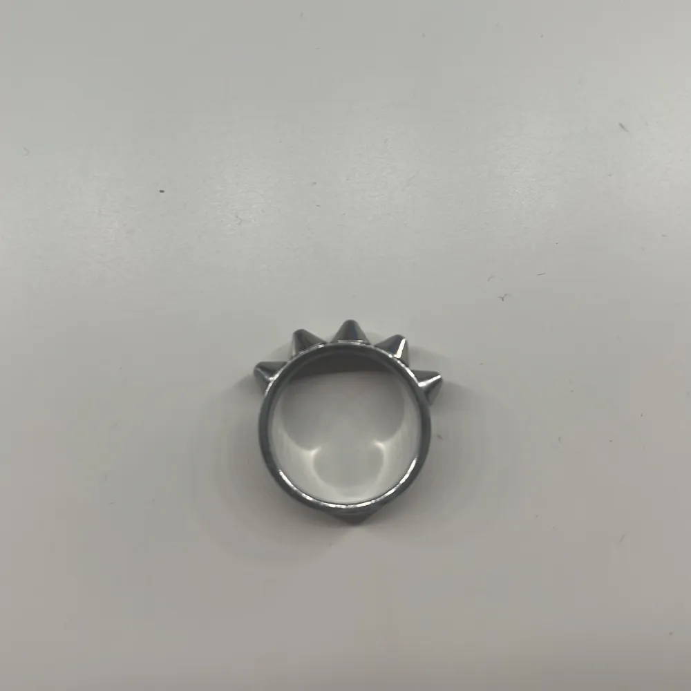 Cool och edgy ring i silverfärg med fem spetsiga nitar runt om. Perfekt för att ge din stil en tuff touch. Passar både till vardags och speciella tillfällen. Säljer då jag bytt till guld oandvänd😝. Asusteet.