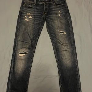 Slitna jeans från Jack & Jones - Snygga jeans från Jack & Jones med slitna detaljer för en cool look. Modellen är Slim/Glenn och har en slim passform. Perfekta för en avslappnad stil. Finns ett hål annars är de bra skick. Skriv vid frågor och funderingar🤝