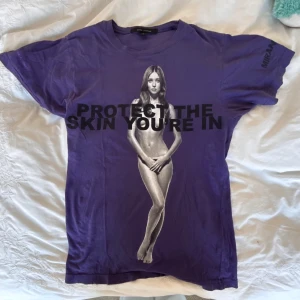 Lila t-shirt från Marc Jacobs - Säljer en lila t-shirt från Marc Jacobs med tryck av en person och texten 'PROTECT THE SKIN YOU'RE IN' på framsidan. Extremt svår att få tag i