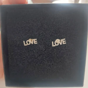 Silverfärgade örhängen med texten LOVE - Snygga och stilrena örhängen i silverfärg med texten LOVE. Passar bra till både vardag och speciella tillfällen.