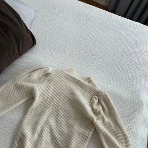 Vit ribbad tröja - Säljer en stilren vit ribbad tröja med långa ärmar. Perfekt för en elegant och enkel look. Tröjan har en klassisk design som passar till många olika tillfällen. Från only