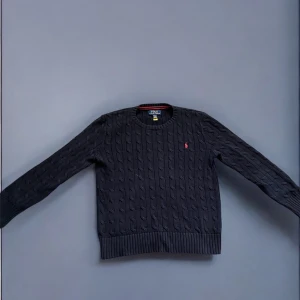 Svart stickad tröja från Ralph Lauren - Säljer en stilren svart stickad tröja från Ralph Lauren med kabelstickat mönster. 10/10 skick, väldigt svår att få tag i idag. Storlek 146-152/ 10-12 år