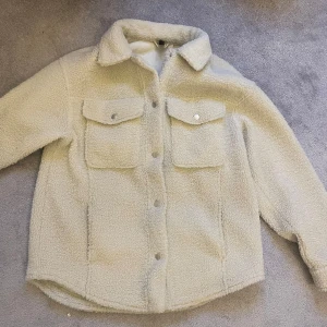 Vit teddyjacka med knappar - Mysig vit teddyjacka med knappar framtill och två bröstfickor. Perfekt vårjacka. Strl S från H&M