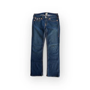 True Religion Billy jeans - Snygga raka jeans med unika broderade detaljer på bakfickorna. De har en klassisk femficksdesign och kontrasterande sömmar som ger en cool look. Perfekta för en avslappnad stil. Inga tydliga defekter. Storlek 29 passar M eller S om man vill ha baggy. Midja 40 innerben 77. De har sytts upp och kan sprättas upp igen om man vill ha längre