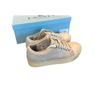 Lanvin ljusgrå/vit - Snygga ljusgrå sneakers från Lanvin med struktur i skinnet och rund tå. Skorna har vita snören och en platt sula med diskret beige kant. Perfekta för dig som gillar stilrena och exklusiva sneakers med en lyxig känsla.