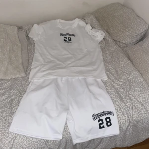 Vit t-shirt Experience 28 tryck - Vit t-shirt med svart tryck fram och bak. På bröstet står det 'Experience 28' och på ryggen ett stort 'Experience' med text och siffran 28. Urban streetstil, rund hals och korta ärmar. Perfekt för dig som gillar grafiska prints och New York-vibe.