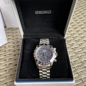 Seiko  Daytona Purple Meteorite kronograf herrklocka - Seiko Daytona Mod Cronograph klocka med urverk i quartz. Har används men ganska sparsamt, därav kan det förekomma små repor men inget som syns tydligt. Tillkommer med påse samt box, enda felet är att när sekundvisaren ställs om så står den ca 1sek innan 12 slaget. Annars väldigt fin och unik. Har ej sett något liknande hos någon annan. 40mm