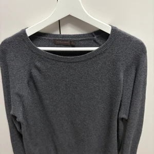 Mörkgrå kashmirtröja Oscar Jacobson - Snygg mörkgrå kashmirtröja från Oscar Jacobson, tillverkad i Italien. Tröjan har rund hals, långa ärmar och ribbade muddar vid hals, ärmslut och nederkant. Perfekt för dig som gillar stilrena och mjuka plagg med lyxig känsla. 