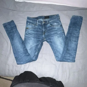 Tiger of sweden jeans - Säljer ett par blå skinny jeans med snygga slitningar och tvättade detaljer. Jeansen har klassisk femficksdesign, smal passform och normal midja. Perfekta för dig som gillar en tajt look och vill ha ett par stilrena jeans till vardags. Modell: slim