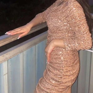 Glittrig champagnefärgad klänning - Säljer en glittrig, figurnära klänning i champagnefärg med trekvartsärm och snygg rynkad effekt. Klänningen har massor av paljetter som ger ett riktigt festligt intryck och är perfekt för dig som vill sticka ut.Klänningen storlek S men jag har själv Xs då det passar även Xs. Priset kan diskuteras:)