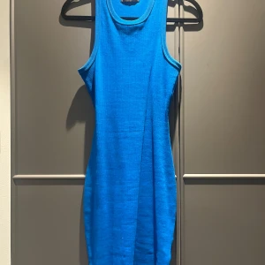 Blå klänning - Snygg blå ribbad klänning i storlek M men passar S och XS. Modellen är ärmlös med rund hals och har en tight passform som framhäver figuren. Materialet är mjukt och stretchigt, perfekt för dig som gillar enkel och stilren design. Använd få gånger. 