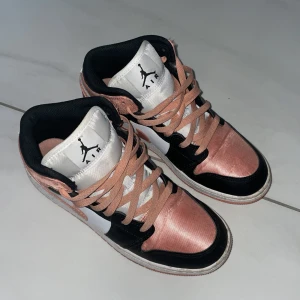 Nike Air Jordan 1 Mid rosa/svart - -Footlockers hemsida har lagts ned men de köptes därifrån för 1 399kr.       -Använda endast 2-3 gånger.      -Jättefina men använder sällan rosa skor, därmed säljs.                                             -Ska rengöras lite innan de skickas iväg.