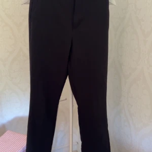 Svarta kostymbyxor från Bik Bok - Svarta kostymbyxor från Bik Bok i klassisk rak modell. Byxorna har en stilren look med normal passform och är perfekta för en clean och snygg outfit. Materialet känns mjukt och följsamt, och midjan är normalhög.