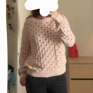 Ljusrosa stickad tröja med hålmönster - Supersöt ljusrosa stickad tröja med hålmönster och ribbade muddar vid ärmslut och nederkant. Tröjan har en rund halsringning och lång ärm, perfekt för lager-på-lager och en chill look.