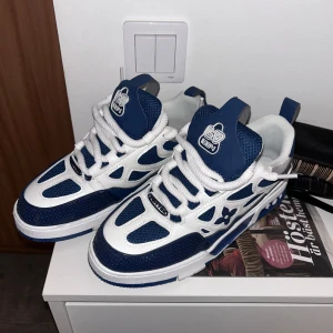 Louis Vuitton blåvita sneakers - Snygga Louis Vuitton sneakers i blått och vitt med chunky sula och coola LV-detaljer på sidan. Skorna har grova vita snören, meshpaneler och läderdetaljer. Perfekta för dig som vill sticka ut med exklusiv streetstyle.