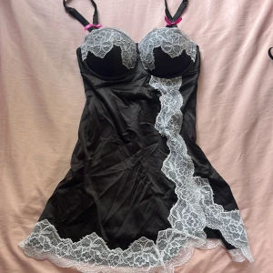 Svart spetsklänning från La Senza - Supersnygg svart kortklänning/lingere från La Senza med vit spetsdetalj. Klänningen har reglerbara axelband med rosa rosetter ❤️ Passar A-B Pris går att diskuteras!