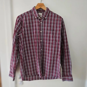 Rutig vinröd skjorta från Dobber - Snygg rutig skjorta från Dobber i vinrött, vitt och mörkblått. Klassisk button-down krage, bröstficka och långa ärmar. Skjortan är i bomull och har en normal passform. Perfekt för dig som gillar en avslappnad men stilren look.