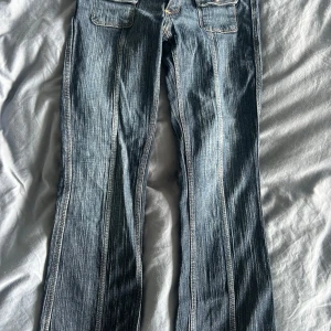 Blå jeans med fickdetaljer och knappar - Säljer ett par blå jeans med coola fickor framtill och dubbla knappar i midjan. Inga fickor bak. Jeansen har tydliga vertikala sömmar och en lätt tvättad look. Snygga kontrastsömmar och klassisk jeansstil, perfekta till sneakers eller boots. Säljer på grund av att de tyvärr har blivit lite små😢🩷