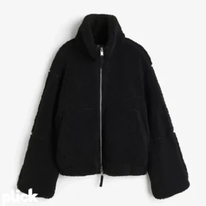 Svart teddyjacka med dragkedja - Mysig svart teddyjacka med hög krage och grov dragkedja framtill. Jackan har en oversized passform och stora fickor, perfekt för kalla dagar. Materialet är fluffigt och ger en cool, avslappnad vibe.