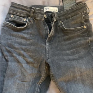 Mörkgrå raka jeans från Zara - Snygga mörkgrå jeans från Zara med klassisk femficksdesign och raka ben. Jeansen har dragkedja och knapp framtill samt bälteshällor. Perfekta för dig som gillar en enkel och stilren look.