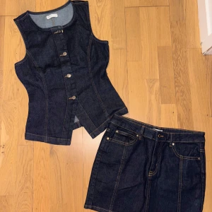 Mörk jeansväst från Perfect Jeans - Snygg mörkblå jeansväst från Perfect Jeans med klassisk rak passform och markerade sömmar. Västen har rund halsringning, knäppning framtill med silverfärgade knappar och är tillverkad i robust denim. Perfekt att styla med kjol eller byxor för en cool look.