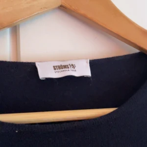 Mörkblå stickad tröja från Ströms - En stilren mörkblå stickad tröja från Ströms med rund halsringning och långa ärmar. Perfekt för lager-på-lager och enkel att matcha med jeans eller kjol. Klassisk modell som funkar året runt.